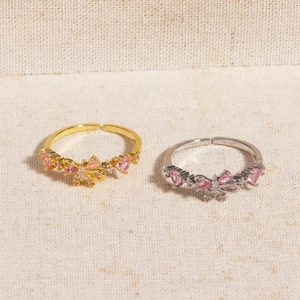 Macro detail of adjustable bow ring with pink heart-shaped zircon in gold and silver