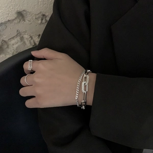 Detail of silver layered chain bracelet with rhinestones and geometric rings on a model