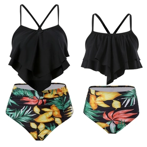 Detail of two-piece tankini swimsuit with black ruffle top and tropical print bottoms