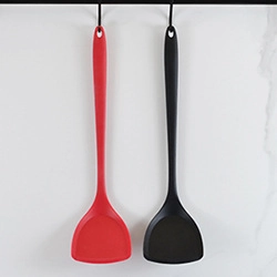 Dettaglio di spatole in silicone rosse e nere con manici lunghi su sfondo bianco