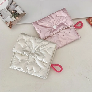 Flat lay of quilted heart clutches in pink and cream with button closure and rope handle