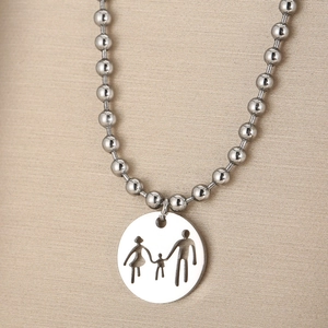 Detailed view of silver steel necklace with hollowed-out family pendant on fabric