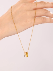 Detail of gold double-ring pendant necklace with colorful zircon and 'with love' engraving