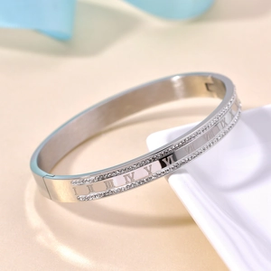 Macro detail of silver steel bangle featuring Roman numeral engraving and zircon pavé