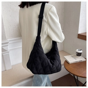 Close-up of black quilted shoulder bag with adjustable strap shown on a model