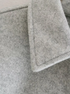 Macro view of light grey wool fabric texture and stitching on the minimalist jacket