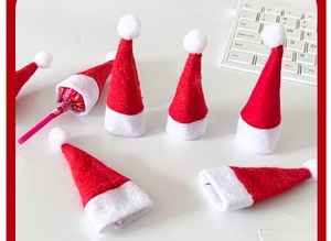 Mini red and white non-woven Christmas hats for lollipops and candy on a desk