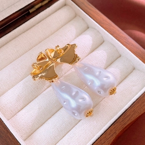 Macro shot of Baroque irregular pearl drop earrings with wavy gold metal in a jewelry box