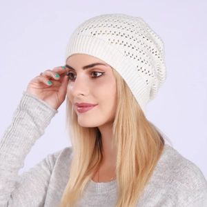 Side view of white knit beanie featuring delicate cutout crochet pattern and ribbed cuff