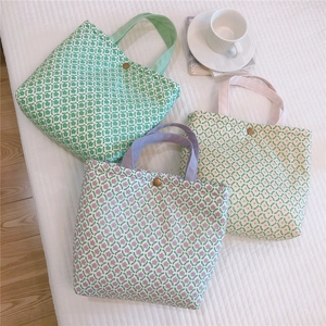 Three floral canvas tote bags in green, purple, and pink floral patterns on white bedding