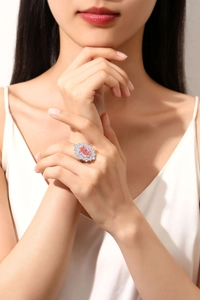 Detail of a pink oval gemstone ring with a halo of small white stones on a silver band
