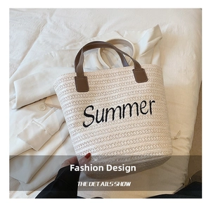 Detail of cream straw tote bag with black Summer embroidery and brown leather handles