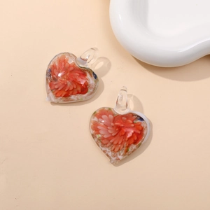 Macro view of heart-shaped glass pendant with orange flowers and gold leaf foil detail