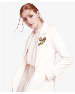 Sparkling rhinestone bow brooch in gold finish pinned on a white blazer collar lapel