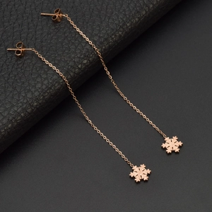 Rose gold snowflake tassel earrings with matte and mirror finishes on a dark surface