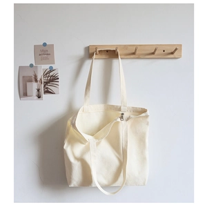 Detailed view of cream canvas tote bag showing top zipper closure and interior space