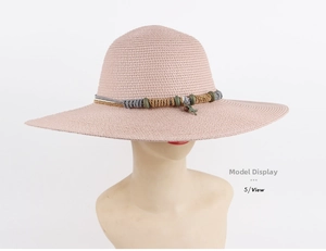 Detail of pink woven straw hat featuring colorful beaded trim and starfish charm