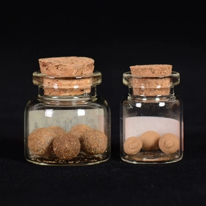 Handmade herbal incense balls in glass jars with cork stoppers on a black background