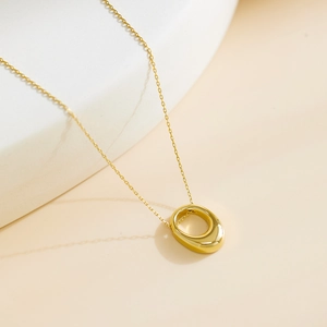 Collier élégant plaqué or avec pendentif ovale minimaliste sur un fond de tons chauds