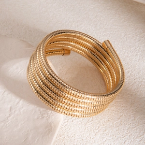 Détail d'un bracelet multi-rangs en maille serpent dorée avec une finition métal polie