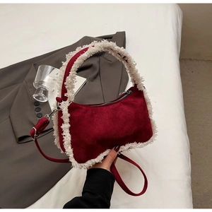 Red suede handbag with beige faux fur trim and silver hardware on white fabric