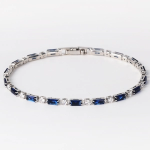 Detail eines silbernen Tennisarmbands mit blauen Rechtecksteinen und weißen Kristallen