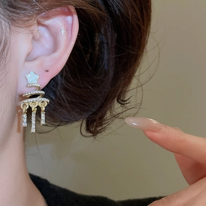 Macro shot of gold spiral Christmas tree earrings with star stud and sparkling tassels