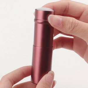 Close-up of retractable makeup brush with burgundy matte case and soft white bristles