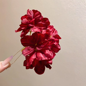 Close-up of deep red fabric flower hair pin with golden metal U-shaped needle detail