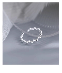 Macro shot of minimalist s925 silver beaded open ring on soft white fabric background