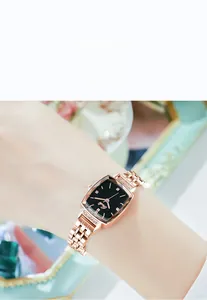 Close-up of rose gold square watch with black dial and diamond accents on a model wrist