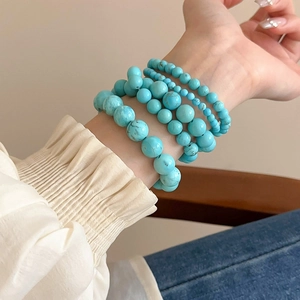 Close-up of stacked turquoise beaded elastic bracelets worn on a female wrist