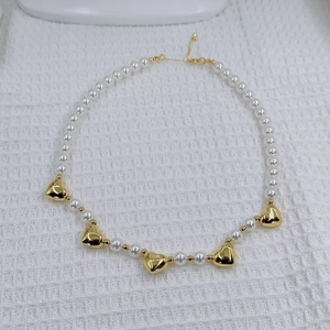 Elegant white pearl necklace with five polished gold heart pendants and adjustable chain