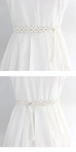 Detail of woven pearl waist chain with large pendant on white dress accessory