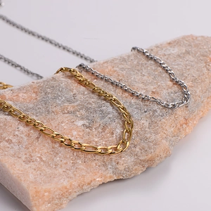 Detailed close-up of gold and silver stainless steel Figaro chains on a natural rock texture