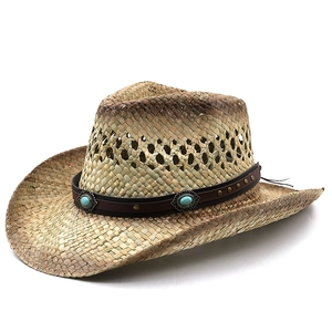 Detail of woven straw cowboy hat featuring turquoise beads and brass rivets on a brown band