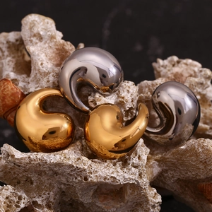 Macro shot of minimalist 18K gold and silver water drop studs on coral stone