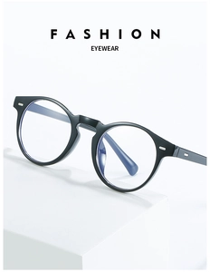 Detail of round black glasses frame with metal accents on a white display stand