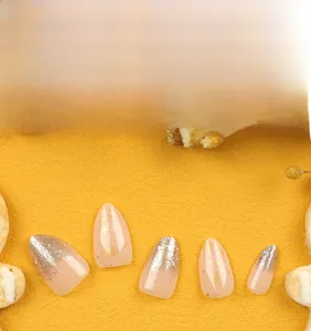 Detailed view of nude pink Christmas press-on nails with silver glitter and gold snowflakes