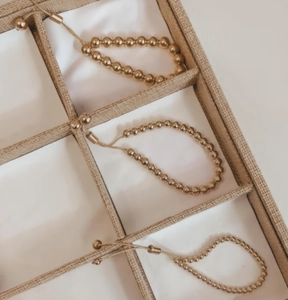 Detailed macro view of adjustable gold-plated bead bracelets with sliding metal clasps