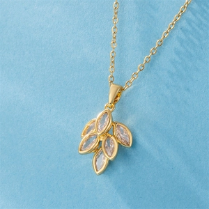 Collier élégant en feuilles dorées avec zircons marquise sur un fond bleu texturé
