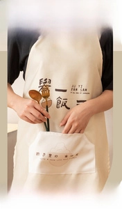Detail of waterproof kitchen apron featuring a large front pocket and minimalist print