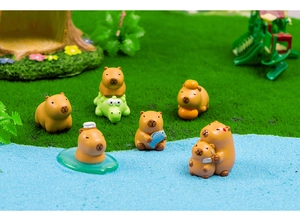 Close-up of cute resin capybara figurines in various poses on a miniature grass landscape