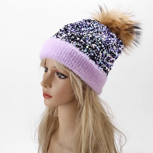 Detail view of purple sequins knit beanie with fluffy brown pom-pom and soft plush brim