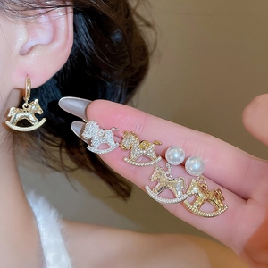 Close-up of model wearing gold and silver rocking horse pearl earrings jewelry set