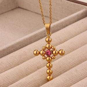 Retro gold cross necklace with pink zircon pendant displayed on a beige velvet tray