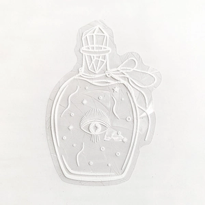 Detailed macro view of white embossed potion bottle sticker with intricate star patterns