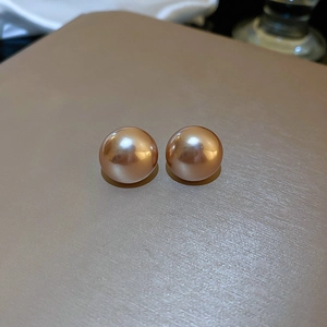 Macro shot of elegant warm pink pearl stud earrings with a glossy polished finish