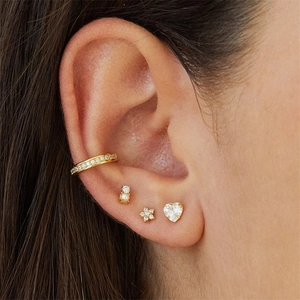 Detailed view of a 4-piece gold flower earring set with pearls and star studs on ear