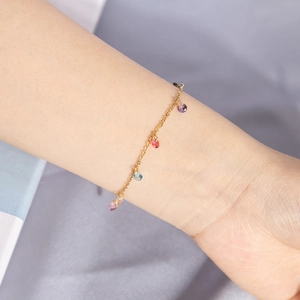 Elegant gold chain bracelet with colorful teardrop gemstones worn on wrist